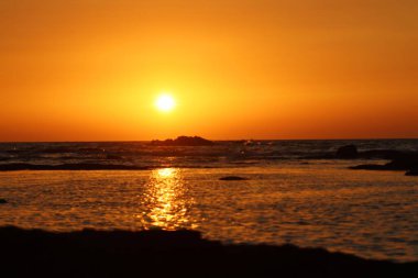 Güneş denizde batıyor ve güzel turuncu gökyüzü tüm deniz köşesini güzelleştiriyor.