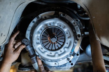 Tamircide çalışan oto tamircisi. Tamirci elleri. Arabaya yeni debriyaj plakası takılıyor, debriyaj sistemi, garajda oto tamircisi, servis debriyajı sistemi..