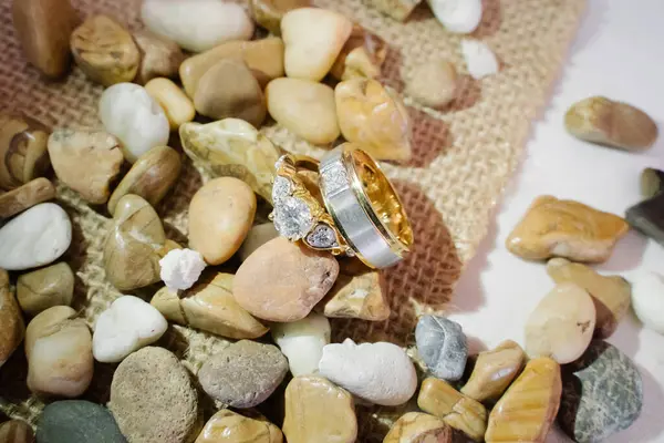 Çakıl taşlarının ve taşların arka planında alyans, altın yüzük, Dimond yüzüğü.,