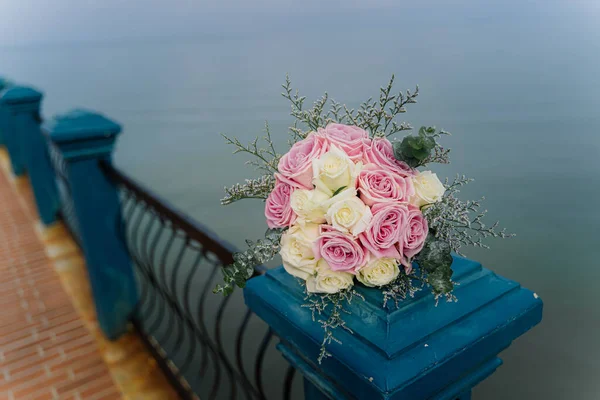Düğün buketi köprüde, deniz dibinde. Bir buket beyaz ve pembe gül..