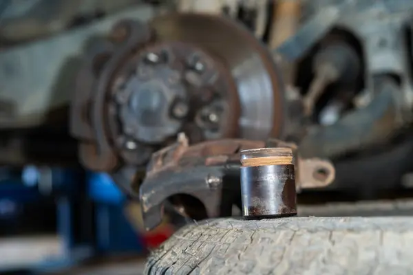 Eski Disk Fren Kalireği Pistonu. Oto tamirhanesindeki tezgahta duran tamirci aletleri. Seçici odak.