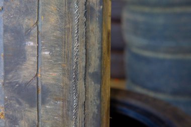 Garajdaki eski araba lastiği, seçici odaklı fotoğrafa yakın çekim. Lastikler hasar görmüş ve süresi geçmiş. Eğer bir kablo görürseniz, hemen değiştirilmeleri gerekir..