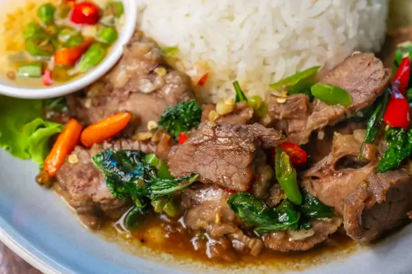 Balık soslu, kırmızı biberli, ahşap bir masada salatalık ve marullu fesleğenli kızarmış biftek..