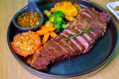 Bir tabakta Sulu Biftek Orta pişmiş, yemeye hazır. Fırında sebzeli ızgara biftek, yakın.