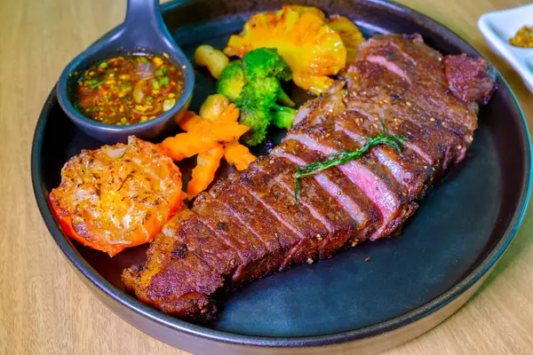 Bir tabakta Sulu Biftek Orta pişmiş, yemeye hazır. Fırında sebzeli ızgara biftek, yakın.