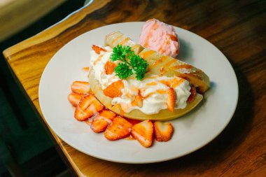 Ballı ve dondurmalı çilekli krep. Dondurmalı krep ve beyaz tabakta çilekli..