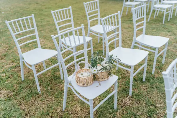 Düğünde çimenlerin üzerine beyaz sandalyeler ve sepetteki düğün çiçeklerini kurun. Bahçe düğün dekorasyonu