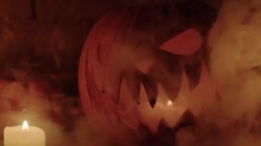 Cadılar Bayramı 'nın özellikleri. Cadılar Bayramı. Oyulmuş balkabağı. Mumlar. Duman. Karanlık sahne. kabak kafalı siluetler.