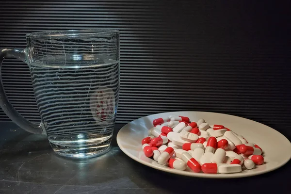 Białe Czerwone Tabletki Talerzu Szklankę Wody Zbliżenie Pojęcie Zdrowia Leczenia — Zdjęcie stockowe