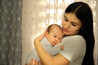 Anne kucağında bir çocuk, kollarında bir bebek. Çocuk uyumak istiyor..