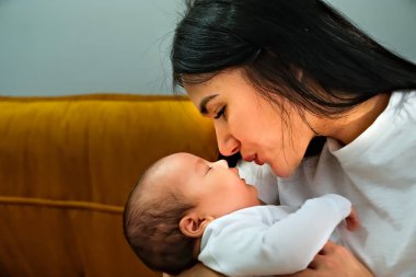 Anne kucağında bir çocuk, kollarında bir bebek. Çocuk uyumak istiyor..