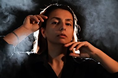Karanlıktaki bir kızın silueti. Duman. Buhar. Karanlık bir odadaki kız.