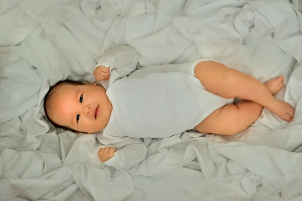 新生婴儿笑着 表现出感情 婴儿躺在白布上 — 图库照片