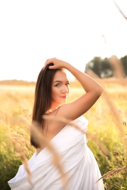 Beautiful young woman in wheat field at sunset. Healthy lifestyle.