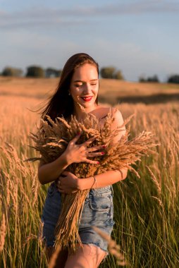 Beautiful young woman in a wheat field at sunset. Beauty, fashion.