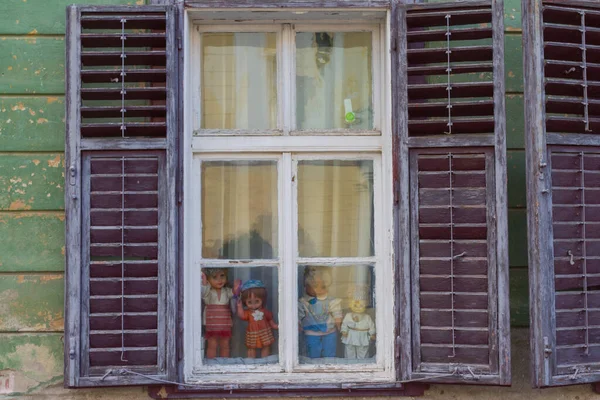 stock image Vintage dolls in an old wooden window on the street of Sibiu. Transylvania. Romania