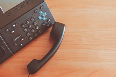 Siyah masaüstü tuşlu telefon. Ofisteki masada IP telefonu var. İletişim konsepti. yakın plan