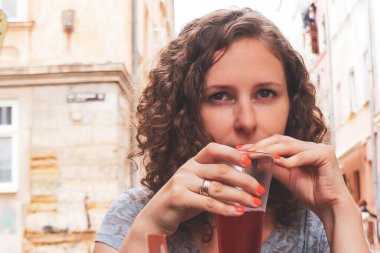 Caddedeki kafede bir kız, kokteylli bir müşteri, kokteyl içiyor.