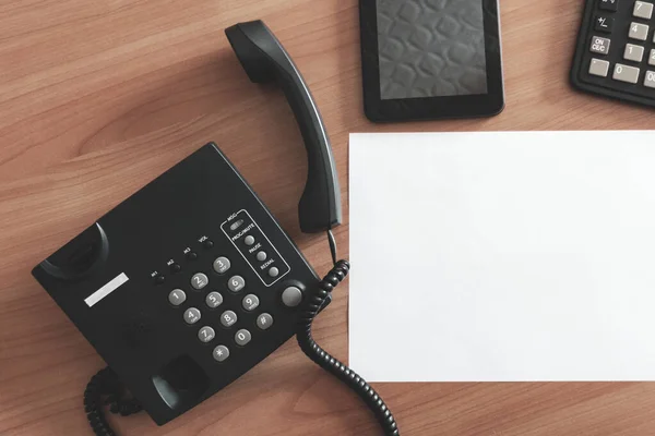 The black desktop  telephone on the table.  phone on desk in office. communication concept. close-up