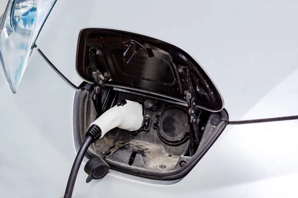 stock image Close up of the power supply plugged into an electric car.Close up image of the power socket of an electric car, charging. Eco-friendly alternative energy concept