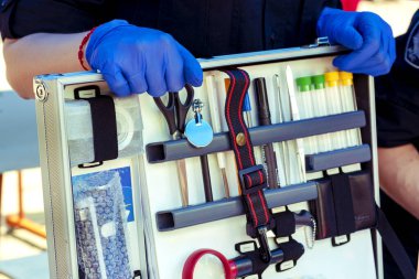 Adli Tıp Uzmanı. İçinde araştırma aletleri olan adli tıp çantası. Eldivenler konusunda kriminoloji uzmanı. - Yakın çekim. Polis uzmanının bavulu. Polis uzmanı çalışıyor. Olay yerinde inceleme yapma konsepti.