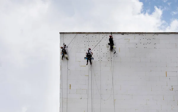 工人们使建筑物的墙壁隔热 高层的工作 工业登山运动 高层建筑物上的一组工人 — 图库照片