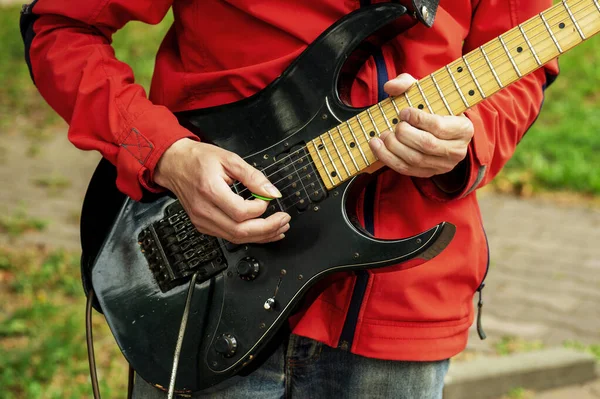 The man holds a guitar in hand. The singer with a guitar. Street actor.  Stringed instrument concept. Close up