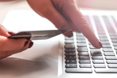 Bilgisayarın arka planındaki enter tuşuna elle basar. El, dizüstü bilgisayar, kart. Ürünleri internetten seçin ve satın alın. Alışverişçi. Konsept çevrimiçi alışveriş, satış. Alıcı kavramı. Müşteriler, alışveriş konsepti  