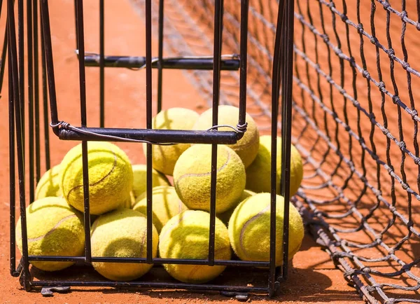 Dünya sahasında büyük tenis topları. Kırmızı toprak tenis kortunda bir sepet sarı top. Spor arenasında konsept çalışma ve eğitim