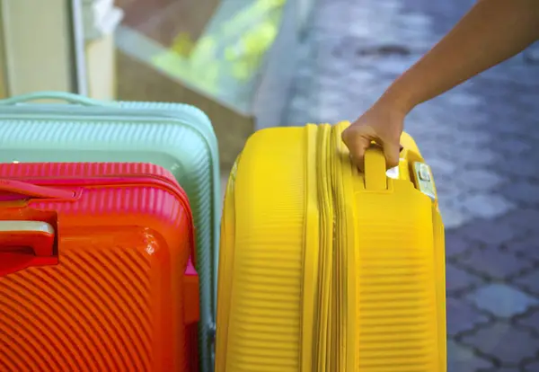 stock image hand holds a suitcase for the handle. Bags for a trip. Colored Bags. Concept moving, travel, trip, flight. Concept Summer rest, holidays. Choosing a suitcase for travel. Hand take luggage carrier