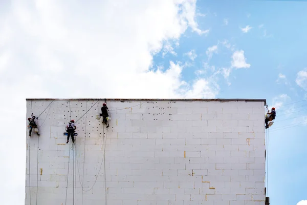 工人们使建筑物的墙壁隔热 高层的工作 工业登山运动 高层建筑物上的一组工人 — 图库照片