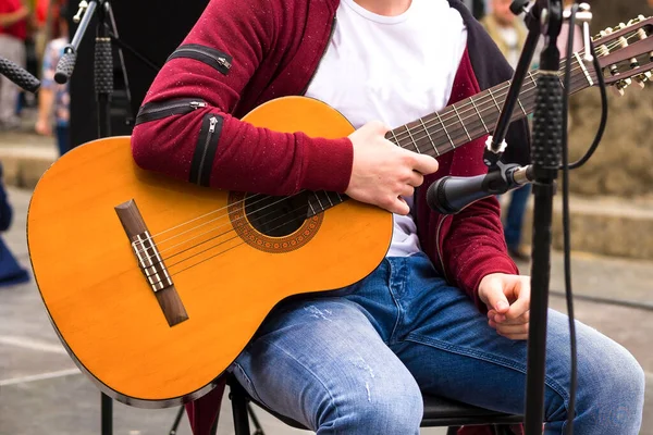 Acoustic guitar. The man holds a guitar in hand. The singer with a guitar. Street actor