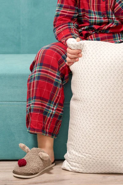 Feet in home pajamas and slippers. Young woman in slippers at home. womans legs wearing pyjamas hanging off bed
