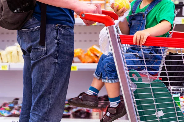 child in the store. girl in the Shopping Trolley near shops. boy and man with trolley on wheels in store. father and son in the supermarket. Concept buyers. Shoppers, shopping concept