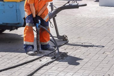 İşçi oyukları sokaktan çekiç taşı blokları topluyor. Şehir caddesinde toplanın..