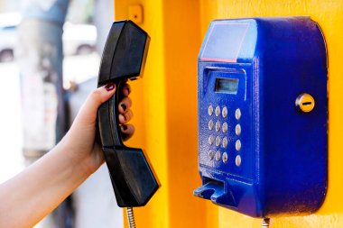 El ankesörlü telefon tüpü tutuyor. Yakın plan. Numarayı elle çeviriyorum. Kanalları ve iletişim türlerini kabul et.
