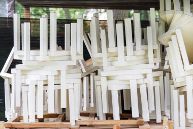 Sandalye taşımacılığı. Bir yığın beyaz dışkı. Mobilya deposu