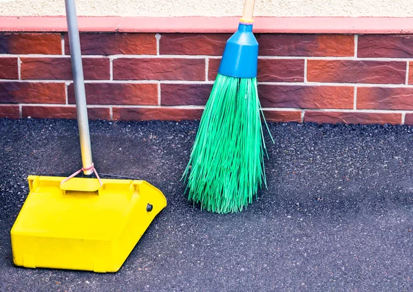 Broom and scoop for cleaning of garbage on the street. The concept Purity on streets. Cleaning of garbage of Outdoors