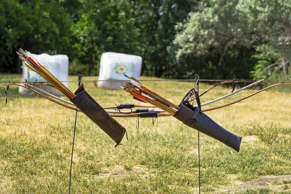 ターゲットの背景に対して矢印を持つ2つの木製の弓 アーチェリーでの競争 矢を撃つための武器 アーチェリー — ストック写真