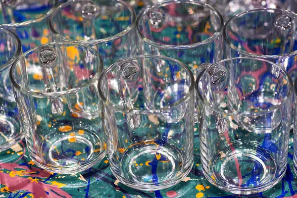 Прозрачные Чашки Цветном Столе Много Стеклянных Чашек Пустые Тарелки Очки — стоковое фото