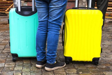 İki renkli bavulu olan kişi. Yolculuk için bavullar. Renkli çantalar. Konsept hareket, seyahat, seyahat, uçuş. Yaz tatili kavramı, tatiller. seyahat için bavul.