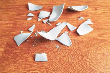 Arka planda kırık bir tabağın beyaz parçaları var. Parçalanmış bir tabağın kıymıkları. Yerde beyaz bir sofra takımının parçaları vardı. Kırık bir tabağın parçaları.