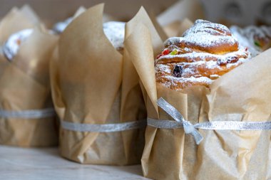 Paskalya pastası pudra şekeriyle tozlandı. Kulich, kağıda sarılmış turta. Pudra şekerli Paskalya keki