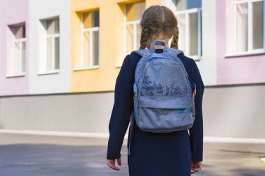 Okulun arka planında bir kız öğrenci. Konsept okul günleri, okula dönüş. Sırt çantalı üniformalı bir kız. Öğrenci, öğrenci, burs. Dikiz aynası.