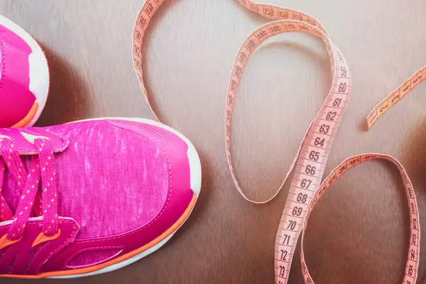 Close up. meter tape, pink sneakers. Concept Healthy way of life. Fitness accessories.The concept of sport. sneakers on background. The first step to a diet and a healthy way of life.