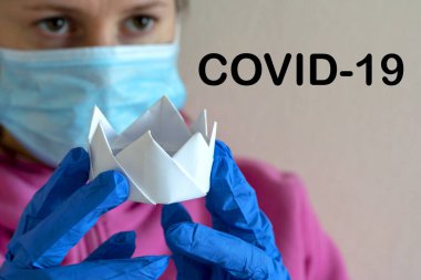 Beyaz taç ve tıbbi eldiven. Üzerinde COVID-19 yazan bir taç tutan bir doktor. Coronovirüs 'e karşı mücadele kavramı. Kavram salgını, koronavirüs, grip.