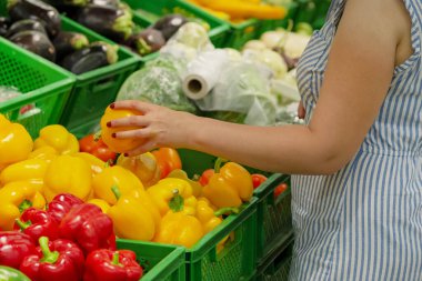 Kadın eli bir süpermarkette sebze alır. Yakın plan. Sarı tatlı biber tutan kız. Kadın bir mağazadan sebze seçiyor. Konsept alıcılar, alışveriş konsepti. biber almak