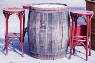 Bar tabureli bar tezgahı. Yazlık bar. Tatil köyünde dinlen. Tahta bir fıçının yanında eski ahşap sandalyeler. Masanın yanındaki sandalyeler. 