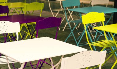 Çok renkli küçük masalar ve sokaktaki tabureler. Renkli demir masalar. Caddedeki kafe.