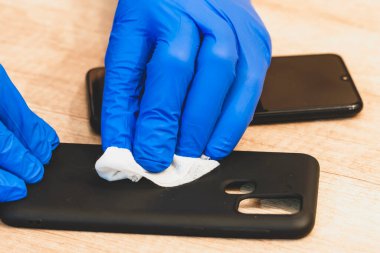 Steril eldivenli eller. Islak dezenfektan, peçete. Cep telefonu, alet çantası. Akıllı telefon çantasının dezenfekte edilmesi, virüslerin ve baterinin yok edilmesi